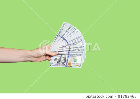 Hand holding a big stack of banknotes isolated on green background. Wealth or loan concept. Banner with copy space Hand holding a big stack of banknotes isolated on green background. Wealth or loan concept. Banner with copy space 81782465