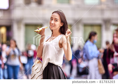 18 year woman speaks on phone on crowded city street. 81783203