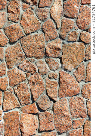 The texture of the wall is lined with red granite stones in the sunlight. 81784761
