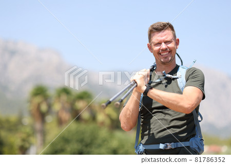 Smiling man holding scandinavian sticks on top of mountain closeup 81786352