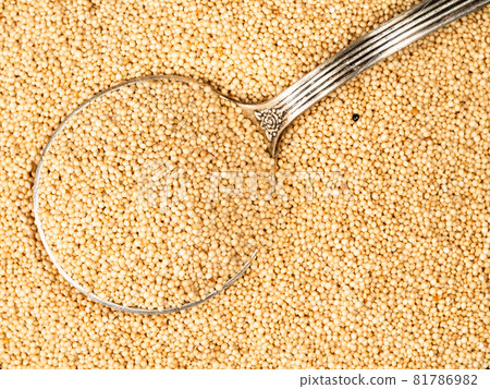 top view of silver tablespoon in amaranth grain closeup 81786982