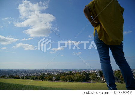在藍天下的草地上,一個女人在後面,從右邊的頭開始,在公園裡,可以看到風景 在藍天下的草地上,一個女人在後面,從右邊的頭開始,在公園裡,可以看到風景 81789747