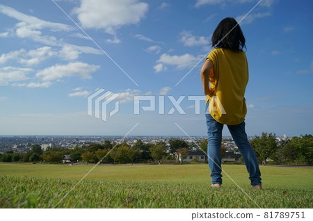 一個女人在後面,雙手叉腰,在藍天下的草地右側,在公園裡可以看到風景 一個女人在後面,雙手叉腰,在藍天下的草地右側,在公園裡可以看到風景 81789751