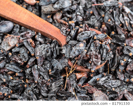 wooden spoon on pile of dried black Berberis fruits closeup wooden spoon on pile of dried black Berberis fruits closeup 81791330