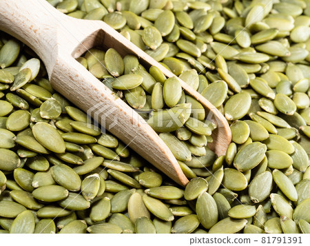 wooden scoop on heap of peeled pumpkin seeds closeup wooden scoop on heap of peeled pumpkin seeds closeup 81791391