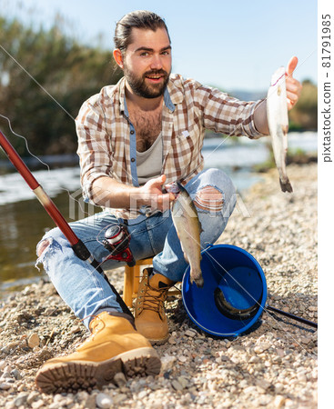 Positive fisherman holding catch freshwater fish in hands Positive fisherman holding catch freshwater fish in hands 81791985