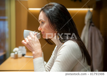beautiful adult woman drinking coffee in a coffee shop beautiful adult woman drinking coffee in a coffee shop 81791986