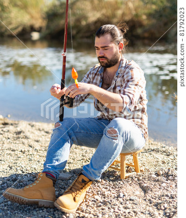 Bearded fisherman prepares fishing gear 81792023