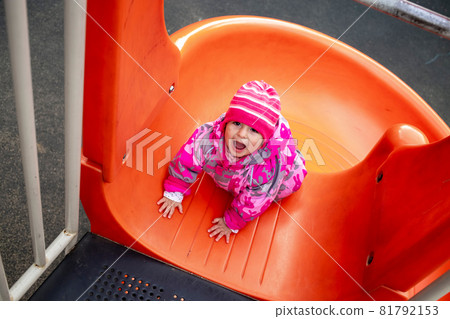 Happy toddler boy playing on a slide at a playground 81792153