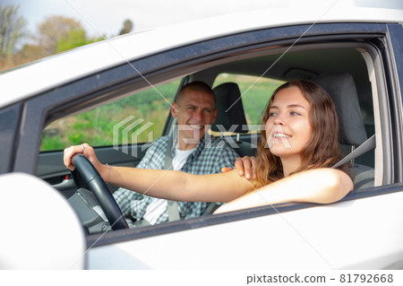 Cheerful girl driving car with boyfriend in passenger seat Cheerful girl driving car with boyfriend in passenger seat 81792668