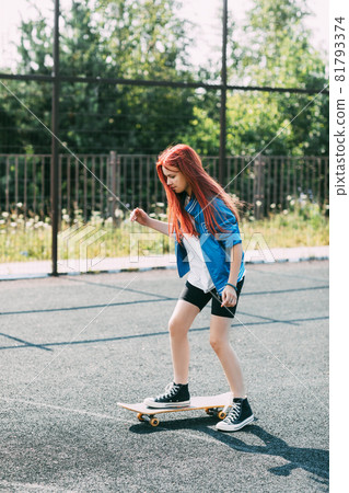 Cute teen girl rides a skateboard on a sports field Cute teen girl rides a skateboard on a sports field 81793374