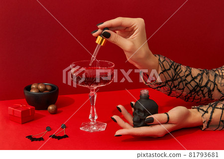 Womans hands with spooky nail design cook cranberry halloween cocktail on red table Womans hands with spooky nail design cook cranberry halloween cocktail on red table 81793681