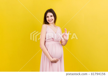 positive pregnant woman showing okay gesture against her belly at colored background. Easy and happy pregnancy. Copy space 81794156