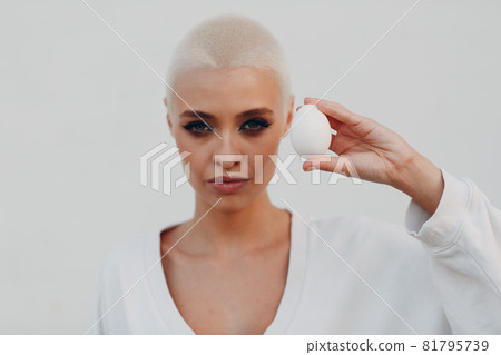 Millenial young woman blonde short hair outdoor smiling portrait with egg. 81795739