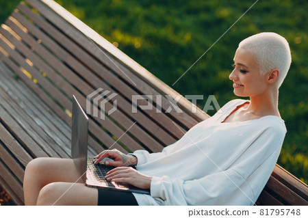 Millenial young woman blonde short hair outdoor smiling portrait with laptop. Millenial young woman blonde short hair outdoor smiling portrait with laptop. 81795748