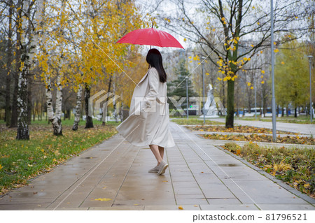 woman in the park dancing under a red umbrella in the rain 81796521