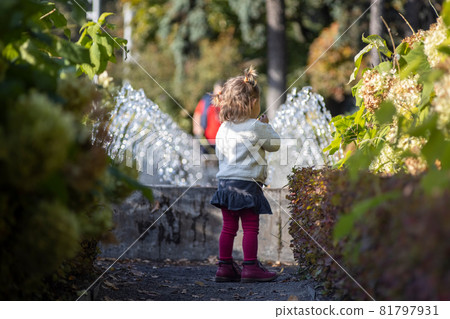 charming toddler in the park with fountains in the background charming toddler in the park with fountains in the background 81797931