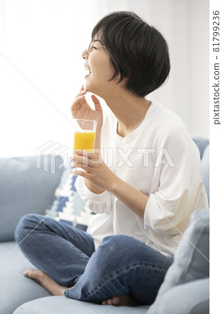 Woman drinking orange juice on the sofa 