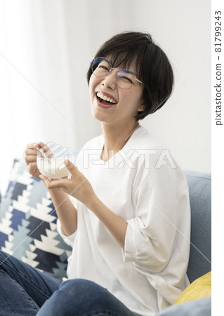 Young woman eating yogurt on the sofa 81799243