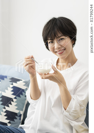 在沙發上吃酸奶的年輕女人 81799244