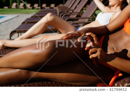 Friends sunbathing on sun beds near the pool 81799652