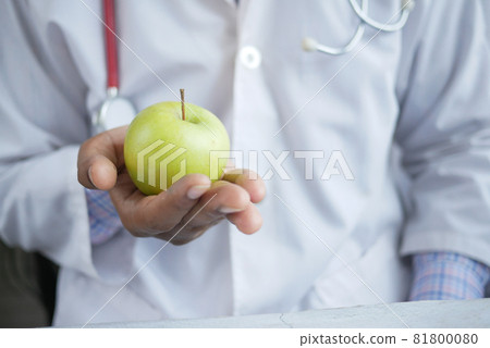 doctor's hand holding green apple while sited 81800080