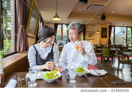 A senior couple enjoying their wedding anniversary at a long-established pizza restaurant with a grand piano 81800300