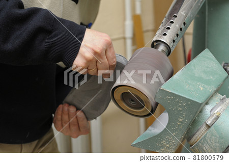 Worker hands sanding wooden blank using a belt grinding machine for further manufacturing prosthesis Worker hands sanding wooden blank using a belt grinding machine for further manufacturing prosthesis 81800579
