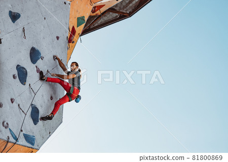 Young man professional rock climber practicing at training center in sunny day, outdoors. Concept of healthy lifestyle, activity 81800869