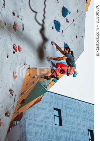 Young man professional rock climber practicing at training center in sunny day, outdoors. Concept of healthy lifestyle, tourism, nature, motion. Young man professional rock climber practicing at training center in sunny day, outdoors. Concept of healthy lifestyle, tourism, nature, motion. 81800876