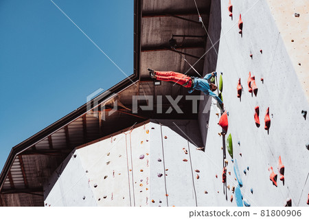 Difficult tricks. Young man professional rock climber practicing at training center in sunny day, outdoors. Concept of healthy lifestyle, activity 81800906