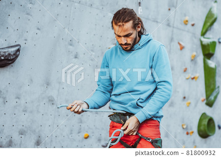 Young man professional rock climber checking sports equipment before climbing at training center in sunny day, outdoors. Concept of healthy lifestyle, activity Young man professional rock climber checking sports equipment before climbing at training center in sunny day, outdoors. Concept of healthy lifestyle, activity 81800932