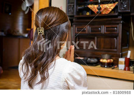 Rear view of a young woman holding hands on a Buddhist altar between Buddhas Rear view of a young woman holding hands on a Buddhist altar between Buddhas 81800988