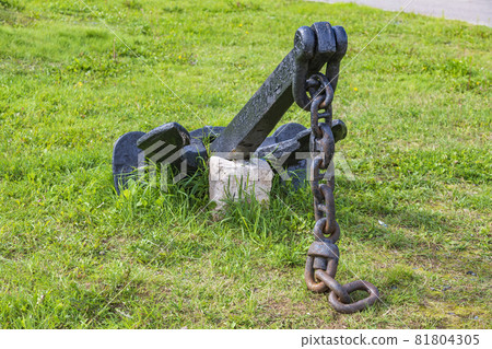 A massive ship's anchor with a chain lies on the grass A massive ship's anchor with a chain lies on the grass 81804305