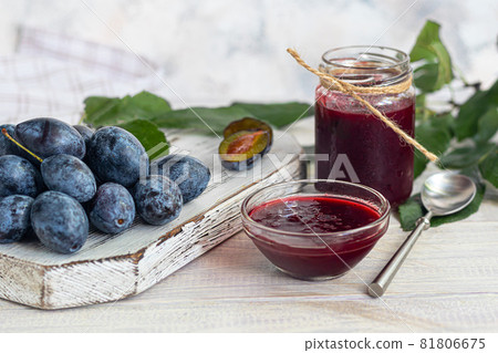 Plum jam in a jar. In the background there are plums. Tkemali sauce. Preparing for winter. Light background. Plum jam in a jar. In the background there are plums. Tkemali sauce. Preparing for winter. Light background. 81806675