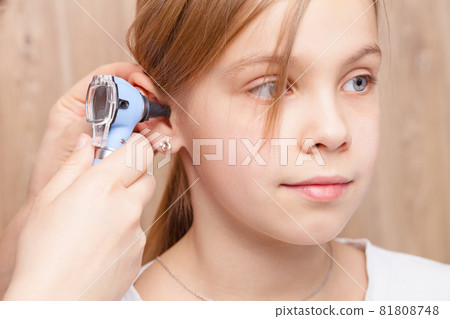 Child ENT check - doctor examining ear of elementary age girl with otoscope 81808748