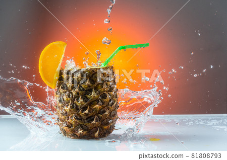 Splashing water around the pineapple. Pineapple cocktail and splash. Red background. 81808793