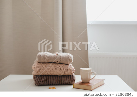 cozy comfortable autumn and winter home atmosphere and still life with a cup, candle, book and sweaters cozy comfortable autumn and winter home atmosphere and still life with a cup, candle, book and sweaters 81808843