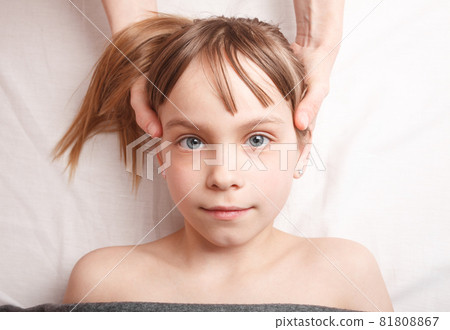 Girl receiving osteopathic treatment of her head Girl receiving osteopathic treatment of her head 81808867