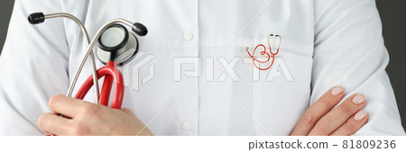 Doctor with brooch on uniform holding stethoscope closeup Doctor with brooch on uniform holding stethoscope closeup 81809236
