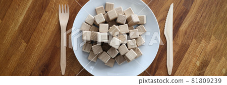 Wooden cubes lying on plate near knife and fork closeup Wooden cubes lying on plate near knife and fork closeup 81809239