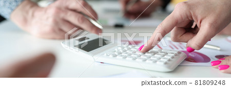 Businesswoman with pink manicure counting on calculator at meeting closeup Businesswoman with pink manicure counting on calculator at meeting closeup 81809248