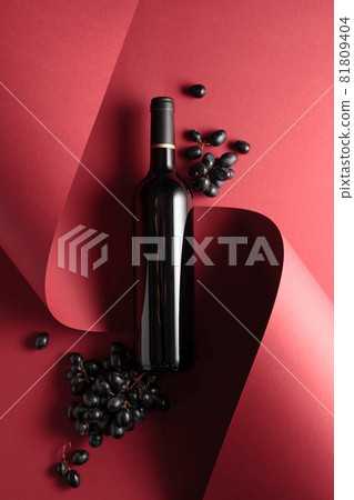 Bottle of red wine and blue grapes. 81809404