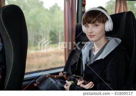 Portrait of content Caucasian student girl in wireless headphones sitting in bus and listening to music Portrait of content Caucasian student girl in wireless headphones sitting in bus and listening to music 81809517