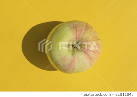 an apple with a hard shadow on a yellow background 81811843