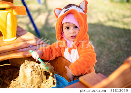 adorable toddler playing in the sandbox. cute child in fox pajamas plays in the sand. portrait of a happy baby 81813059
