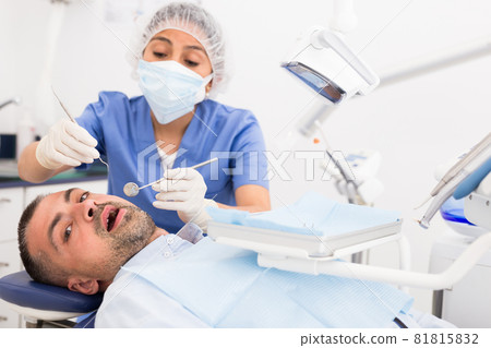 Female dentist in face mask with male patient Female dentist in face mask with male patient 81815832