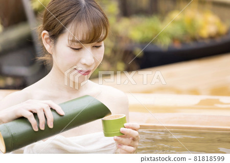 A young woman drinking sake in an open-air bath 81818599