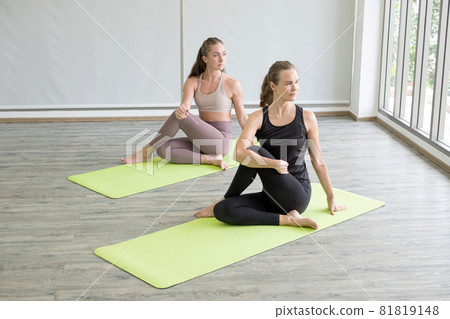 Two young women doing yoga, doing activities together, practicing muscular exercises for good health, and having a happy rest at home 81819148