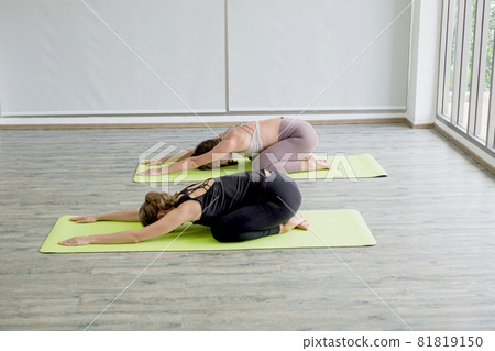 Two young women doing yoga, doing activities together, practicing muscular exercises for good health, and having a happy rest at home 81819150